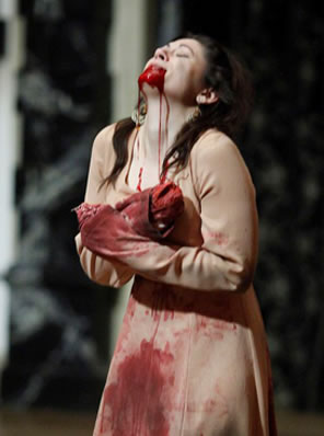 Lavinia, with bloodys tumps for hands, bload soaked dress, and blood spewing from her mouth
