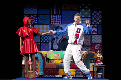 Falstaff in a USA track suit dances with Alice Ford wearing a vinyl Red Riding Hood outfit in a quilt-laden living room