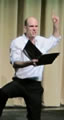 Matthew Fahey as Prince Edward, on his knees, left index finger pointed in the air and reading from a script in his other hand.