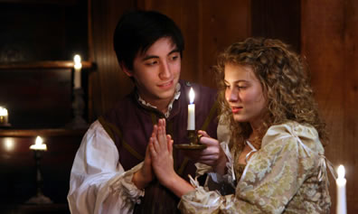 Romeo and Juliet, palm to palm, holding candle, she looking at their joining hands, he looking at her