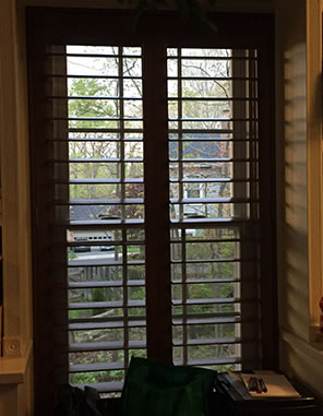 Photograph through the office window seat, with the sun casting shadows through the wood shutters.
