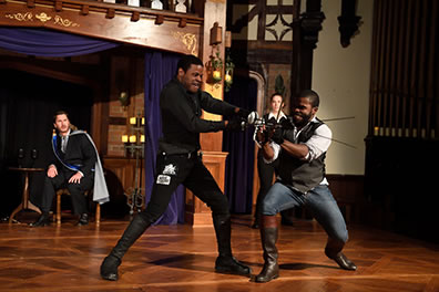 Production photo of Hamlet and Laertes duleing with swords and daggers