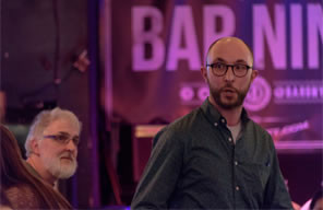 Photo of Jonathan Minton performing Thomas More's speech at Bar Nine, with his father looking on from the side