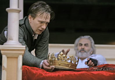Hal holds the crown at the foot of the bed in which King Henry lies