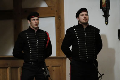 Cassio and Iago in uniform--Cassio's has a red braid on his left shoulder--stands at attention.