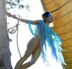 Arial, in silver leaotard, blue shreddy fabric as a shawl, and blue makeup across her forehead and down by her eyes, holds onto a rope around a real tree trunk and leans out with a ship's sail behind her