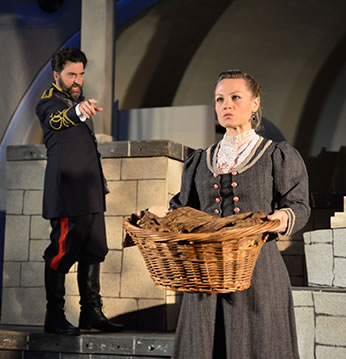 Production pic of Leontes pointing at Paulina holding a basket with the baby